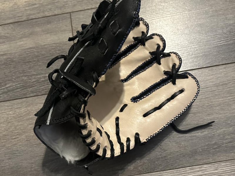 A restored black and cream baseball glove after a full re-lace and deep clean